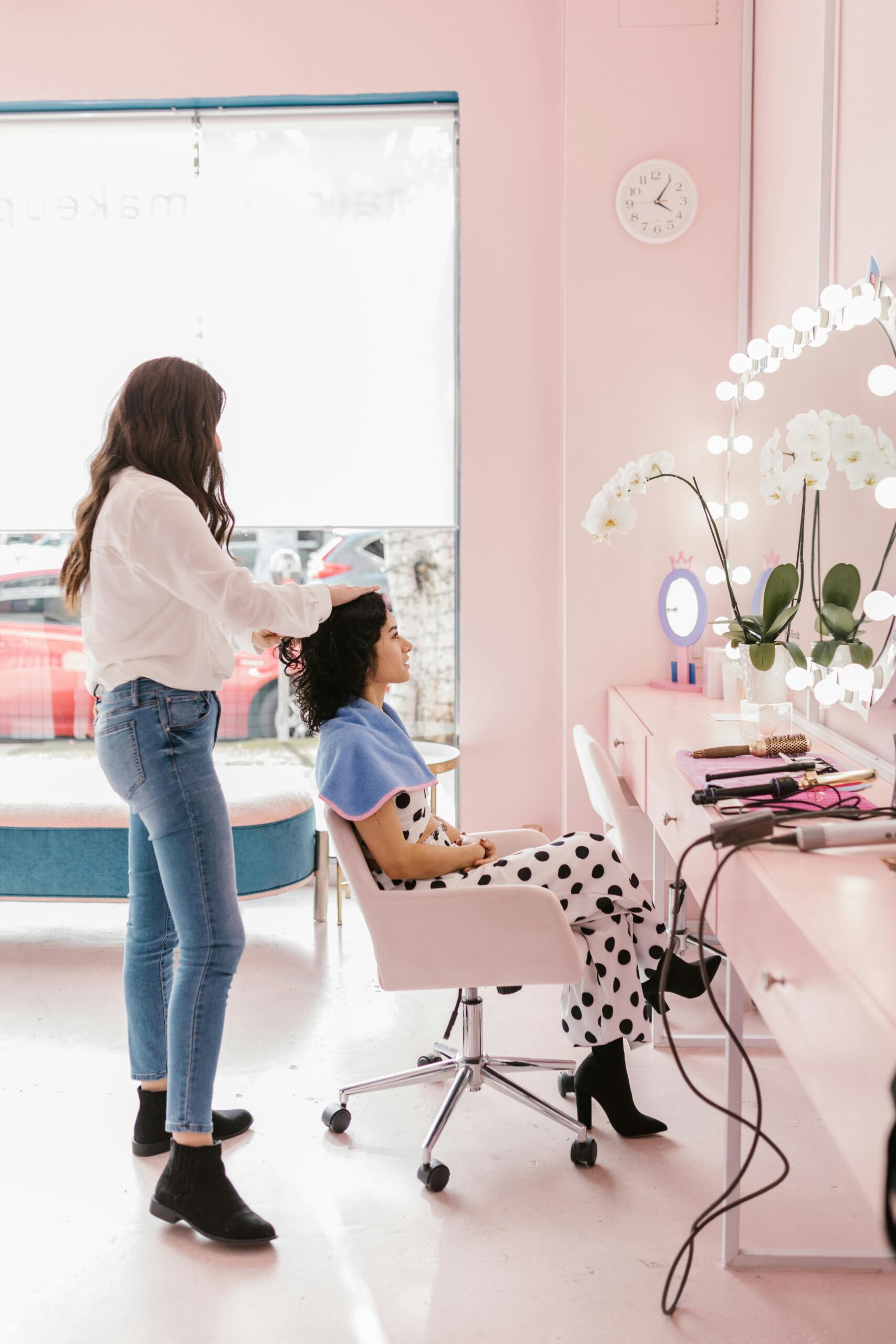 Hairdresser styling client's hair in a modern salon setting with soft lighting.