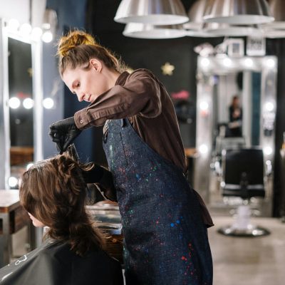 pexels-photo-3993320-3993320 A female stylist expertly applying hair color to a client in a modern salon setting.